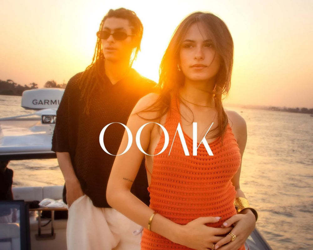 Two people on a boat with 'OOAK' branding at sunset.